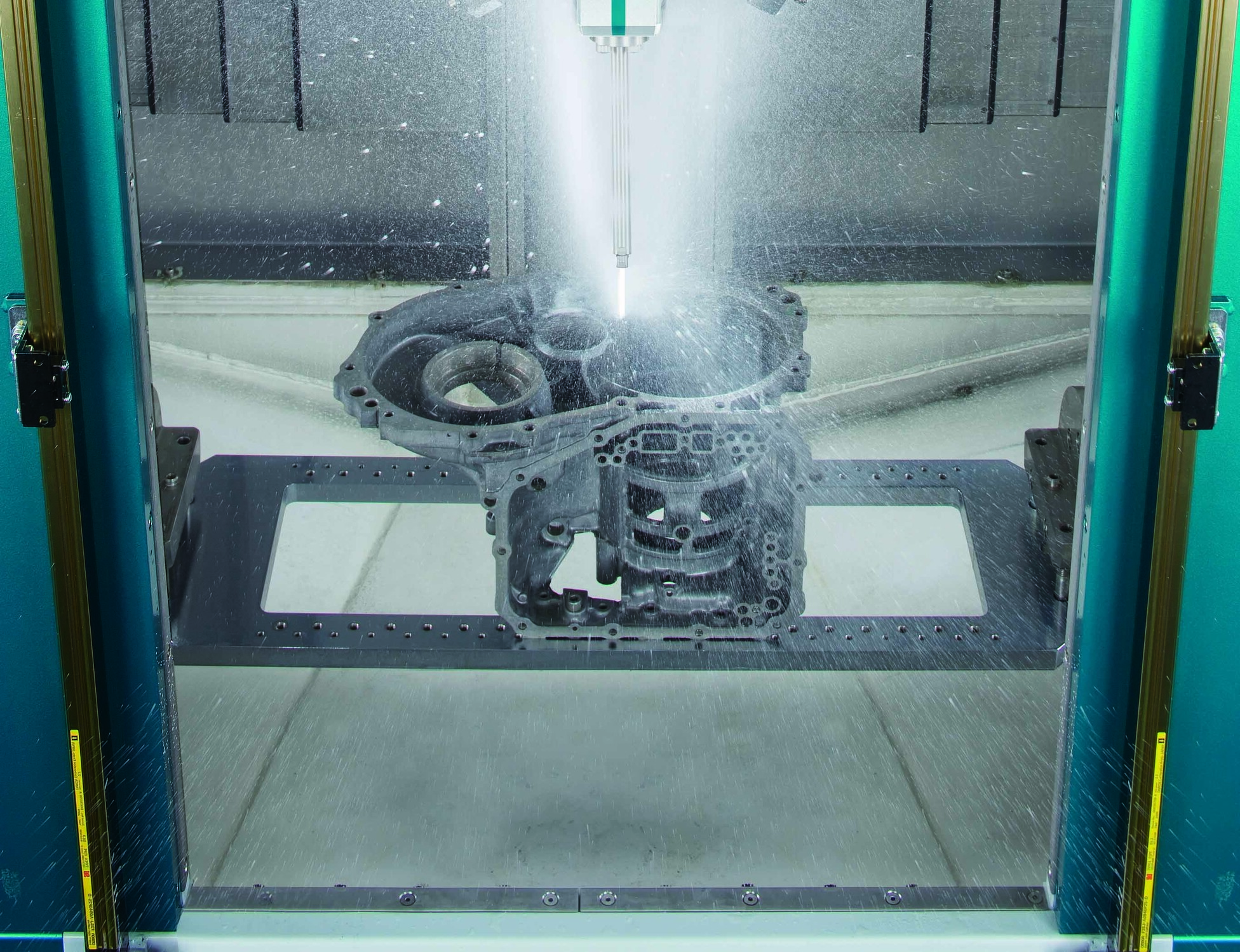 Spraying water to deburr an automotive part inside a Sugino CNC JCC machine.